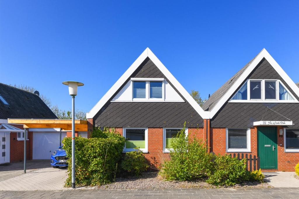 uma casa de tijolos vermelhos com uma porta verde em Haus Nordseepferdchen em Bensersiel