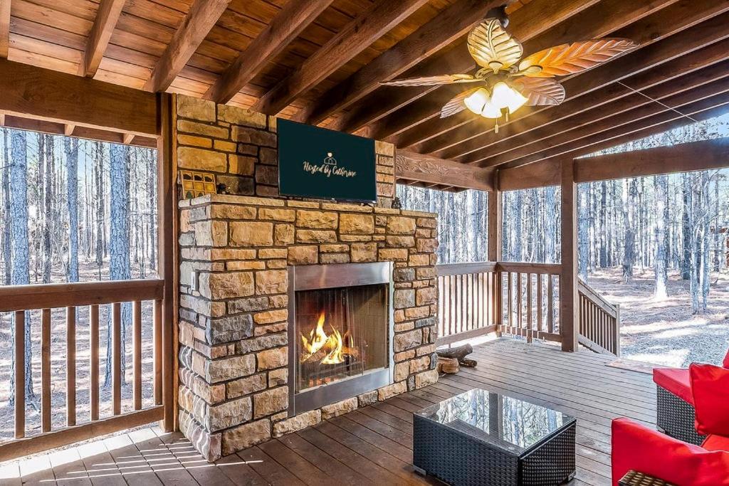 a living room with a stone fireplace on a deck at Large Luxury 2BR Cabin w Hot Tub Double Trouble was designed for fun comfort and memories minutes from buzzling Hochatown and beautiful Beaver Bend State Park in Broken Bow