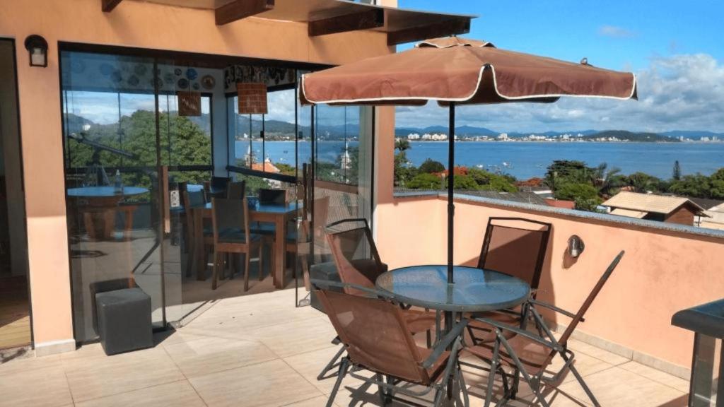 a table and chairs with an umbrella on a balcony at Casa da Flôr GuestHouse, Praia Grande, Beto Carrero in Penha