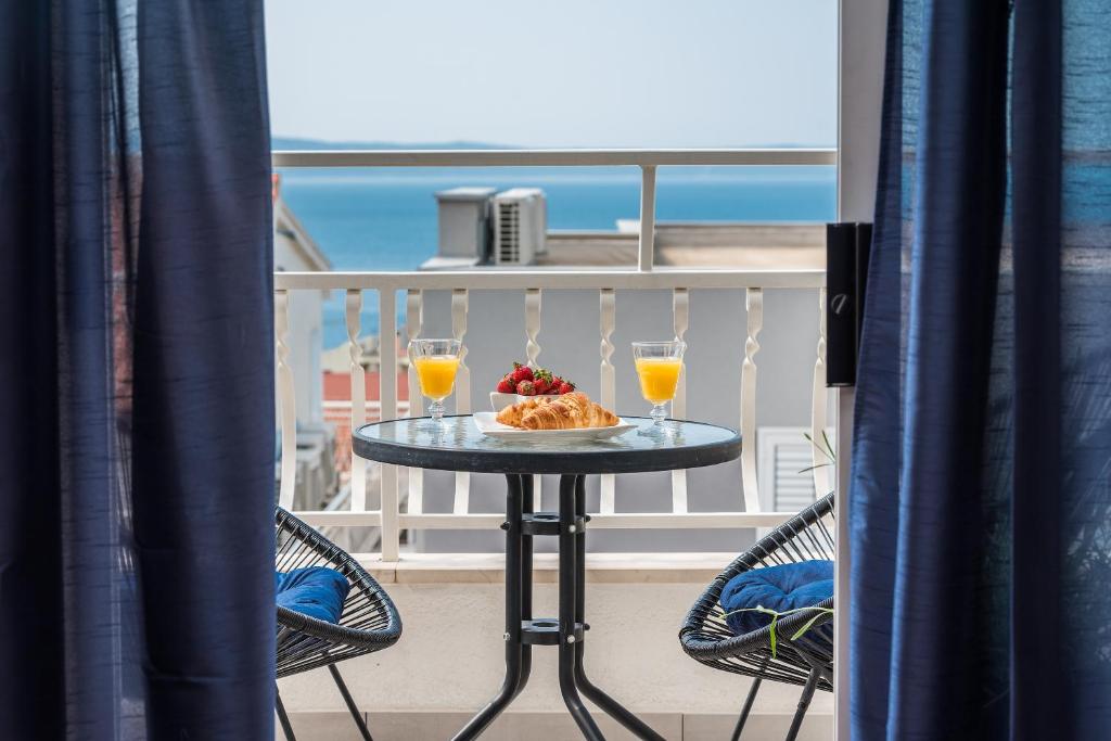 een tafel op een balkon met 2 glazen sinaasappelsap bij Apartman MG Makarska in Makarska