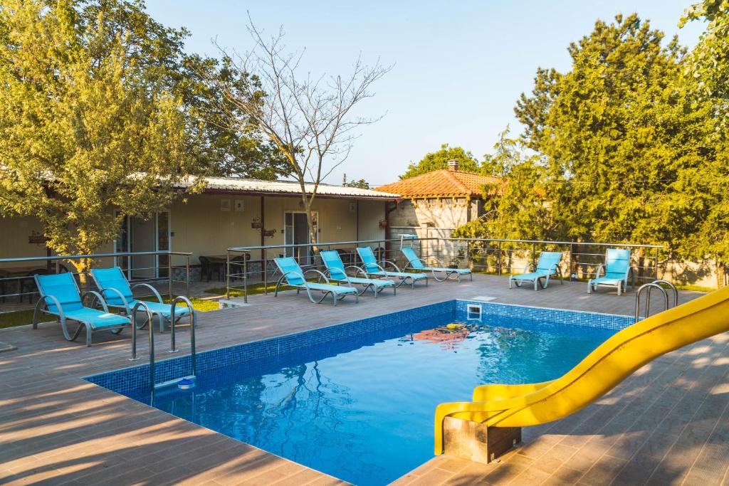 una piscina con sillas azules y un tobogán en Guest House Nevena, en Shabla