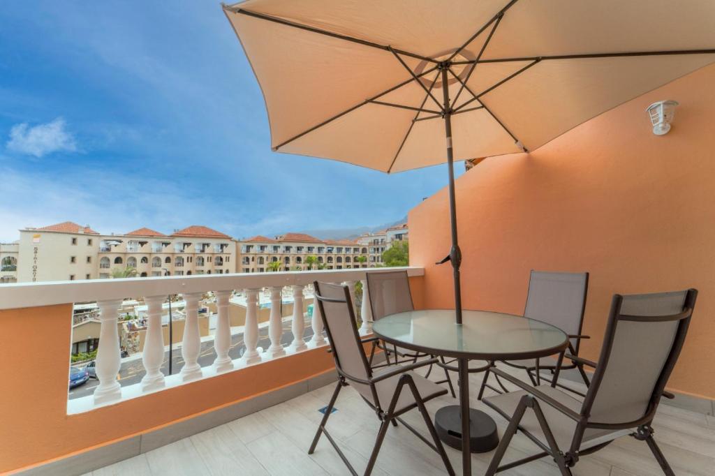 einen Balkon mit einem Tisch, Stühlen und einem Sonnenschirm in der Unterkunft Comfortable Apartment Los Cristianos. Free Wifi. in Arona