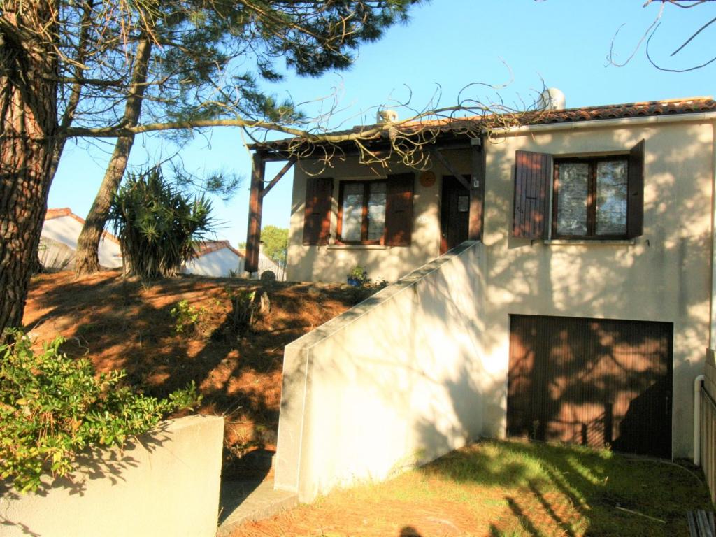 une petite maison blanche avec un mur blanc dans l'établissement Maison boisée proche de la plage des Coraux, 2 chambres, terrasse, parking et jardin - FR-1-22-283, à La Tranche-sur-Mer