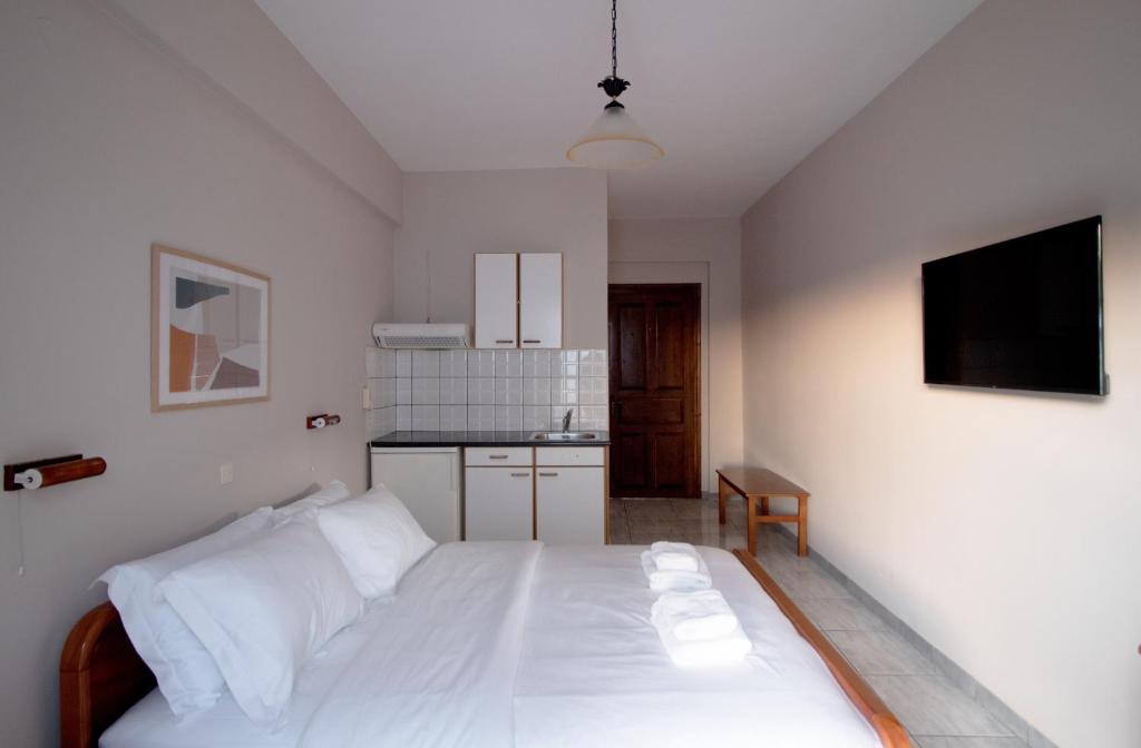 a bedroom with a white bed and a kitchen at Pomelo Rooms in Parga