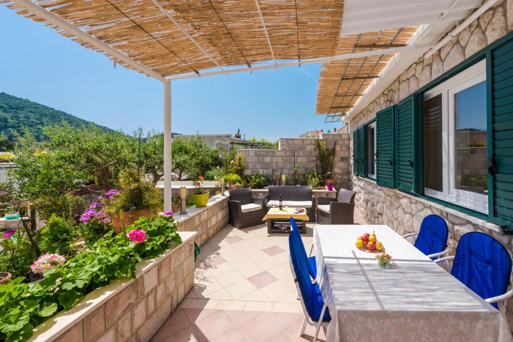 un patio con mesa, sillas y flores en Apartments Maria en Dubrovnik