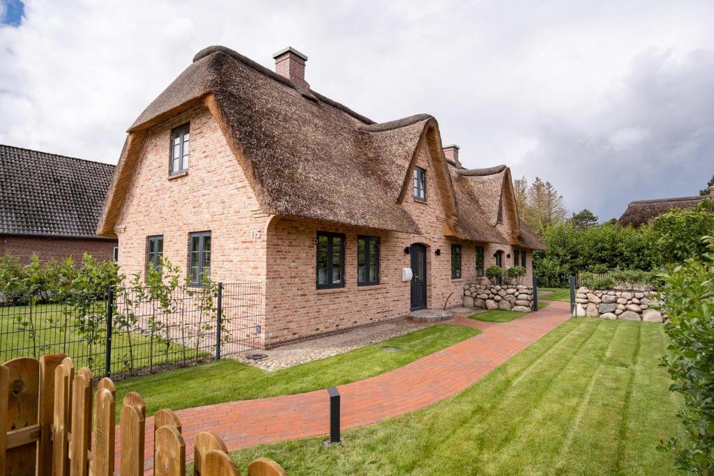 een groot bakstenen huis met een rieten dak bij Ferienhaus Böhler Ferienhaus Böhler 115 a in Westereck