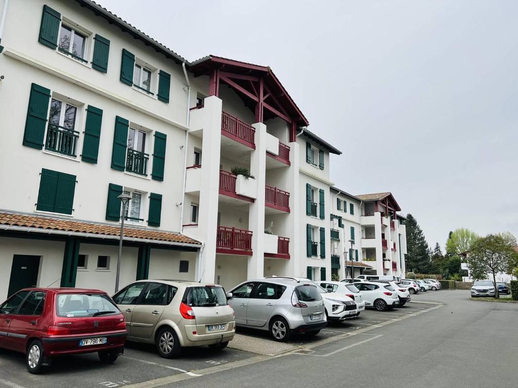 a row of cars parked in a parking lot in front of a building at Charmant T2, centre Cambo, calme, Tt confort, terrasse, parking, proche commerces - FR-1-495-5 in Cambo-les-Bains