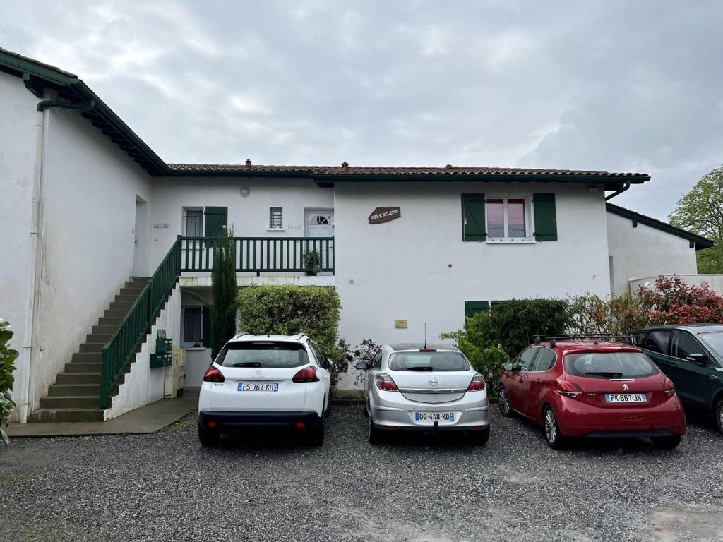 drei Autos auf einem Parkplatz vor einem Haus geparkt in der Unterkunft Appartement Cambo-les-Bains, 2 pièces, 2 personnes - FR-1-495-58 in Cambo-les-Bains