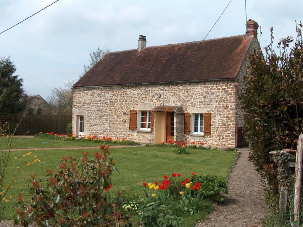 uma pequena casa de tijolos com um quintal com flores em Gîte Vrigny (Orne), 2 pièces, 2 personnes - FR-1-497-32 em Vrigny