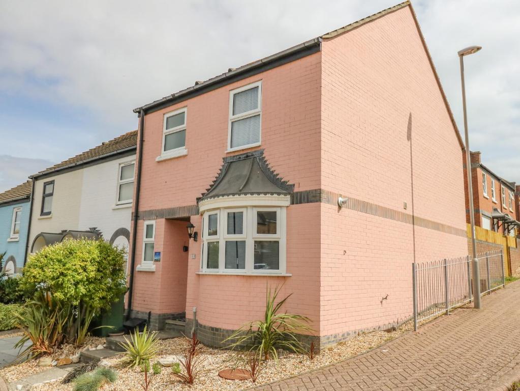 a pink brick house with a black roof at Mermaid House in Weymouth