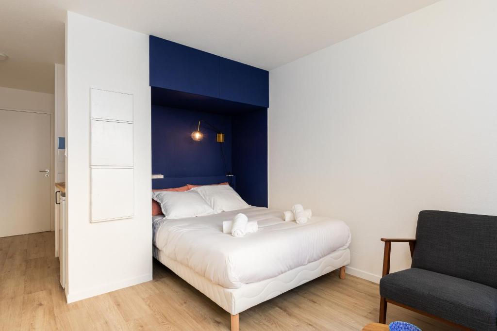 - une chambre avec un lit blanc et un mur bleu dans l'établissement DIFY Eugene - Part Dieu, à Lyon