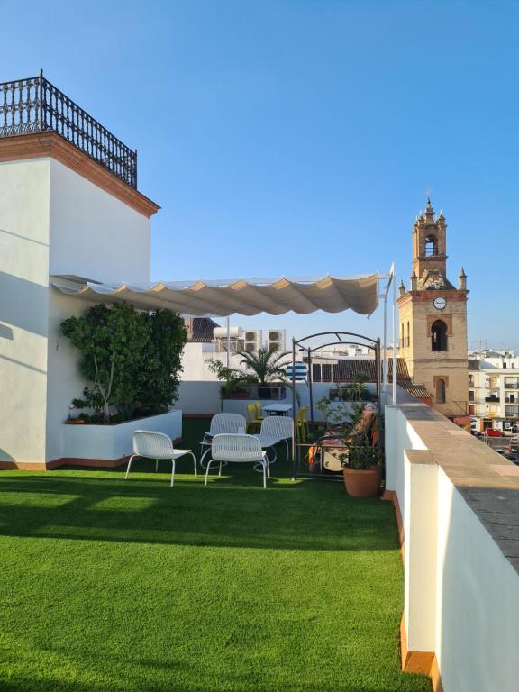 d'un toit-terrasse avec des chaises et une tour d'horloge. dans l'établissement Híspalis Casa Palacio Ático, à Séville