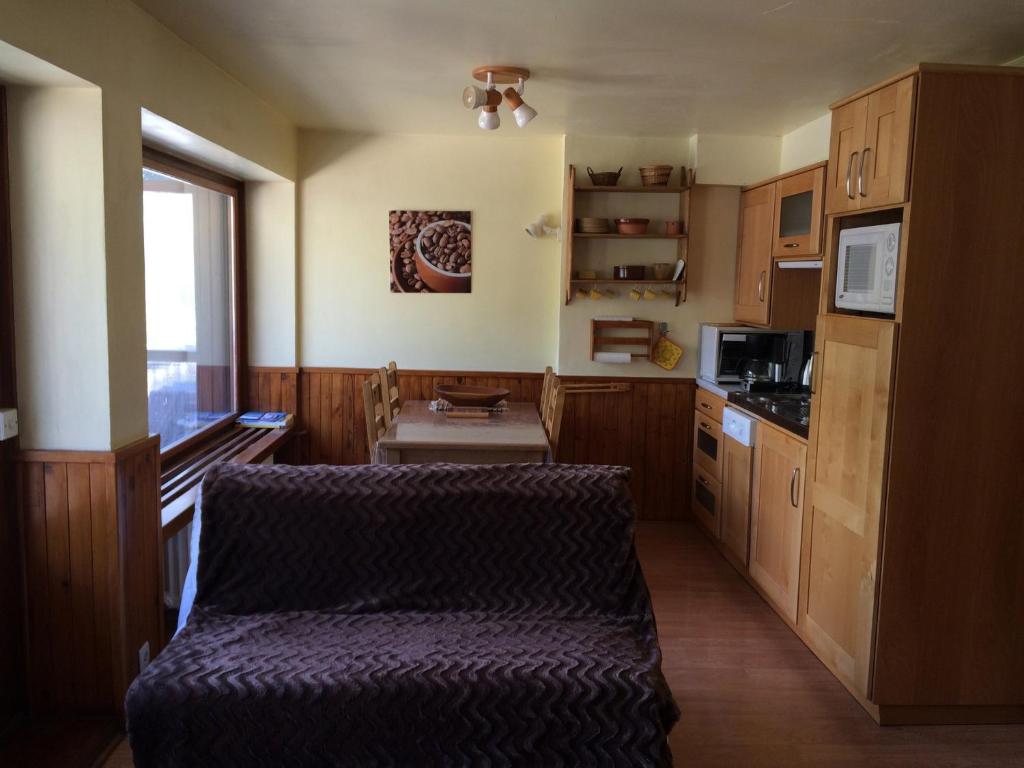 a kitchen with wooden cabinets and a couch in a room at Appartement Valloire, 2 pièces, 5 personnes - FR-1-263-456 in Valloire