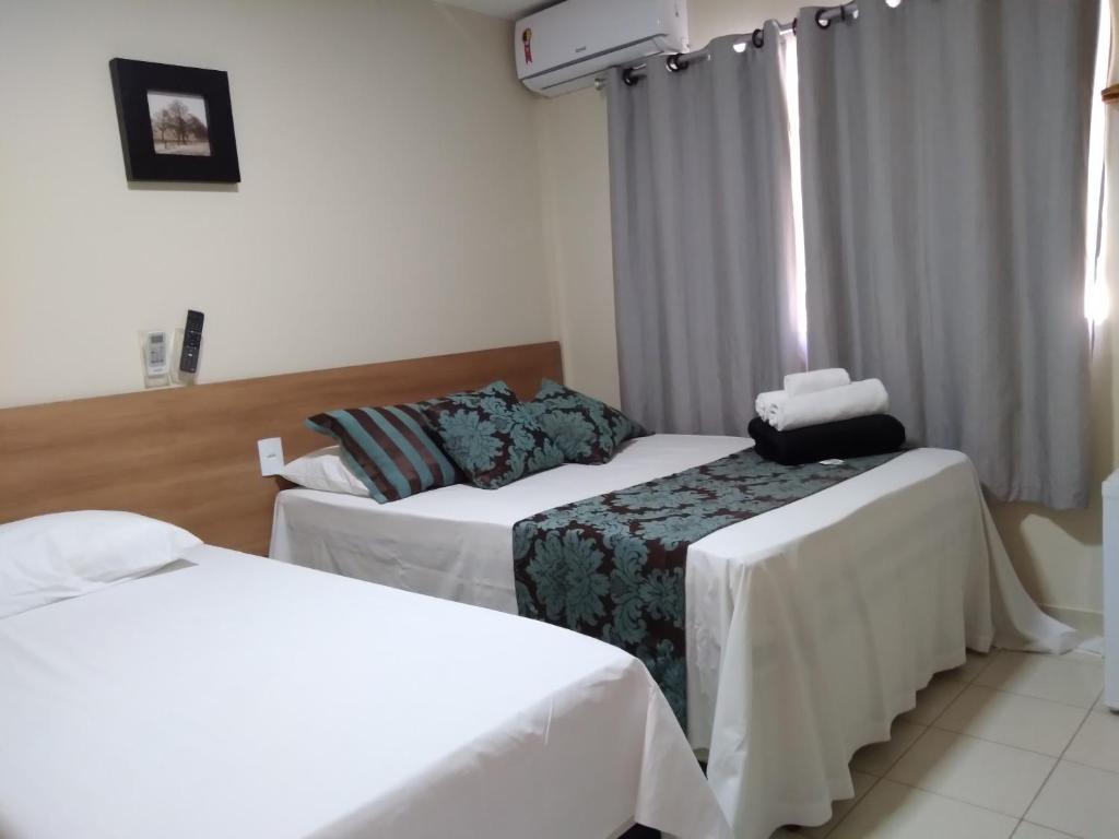 una camera d'albergo con due letti e una finestra di Pousada Solar de Lourdes a Guarapari