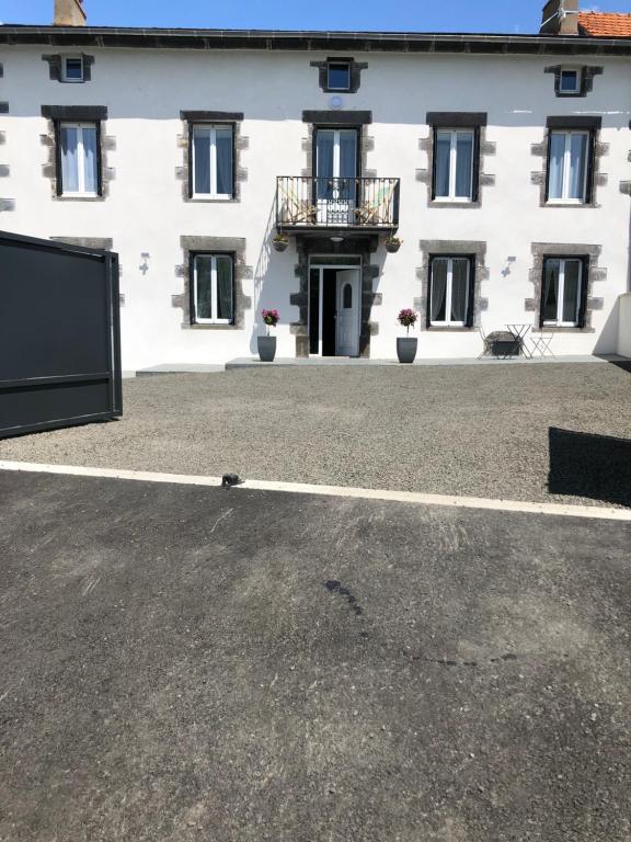 a large white building with a balcony in front of it at Le Burin des Rosiers in Olby