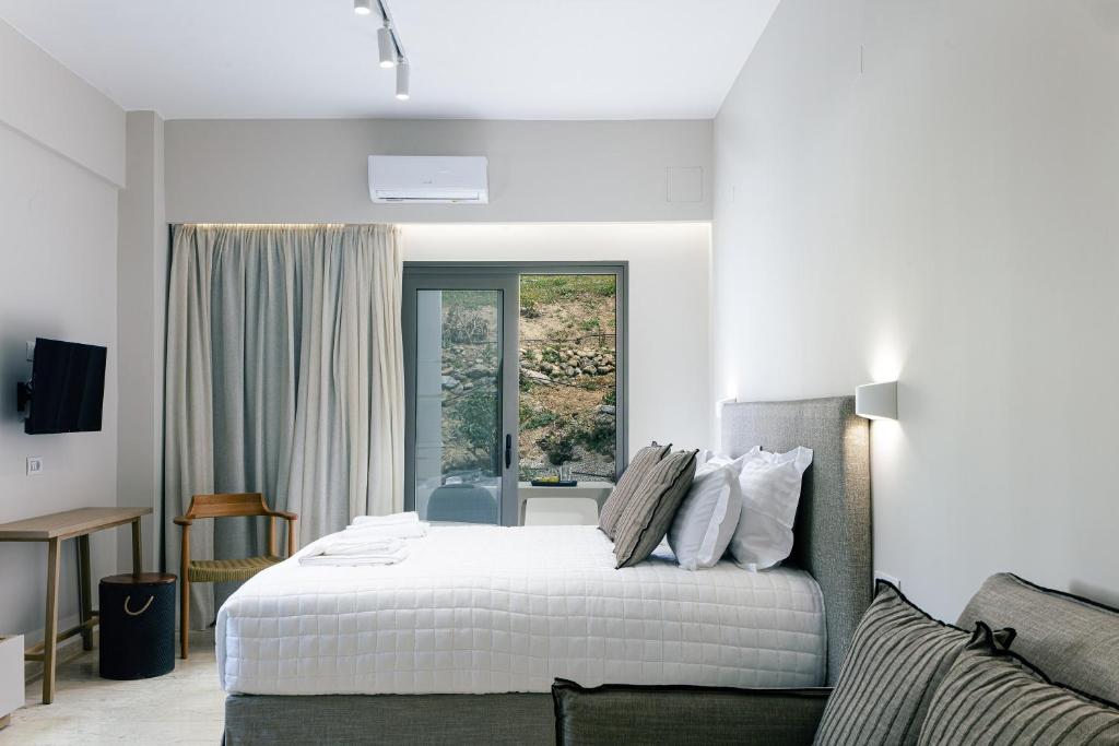 a white bedroom with a bed and a window at Ariadne Suites in Plakias