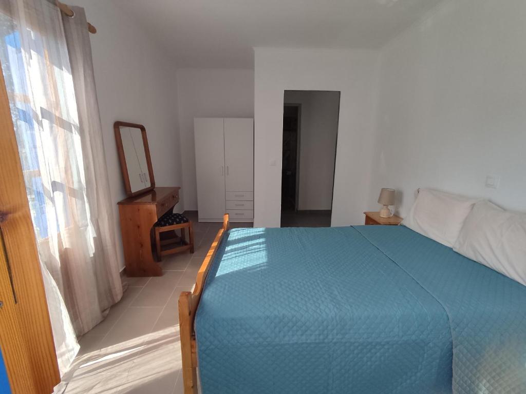 1 dormitorio con cama azul y espejo en Nemesia resort en Anaxos