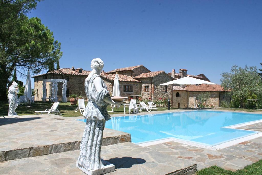 Eine Statue eines Mannes, der neben einem Schwimmbad steht. in der Unterkunft Borgo Di Celle in Città di Castello