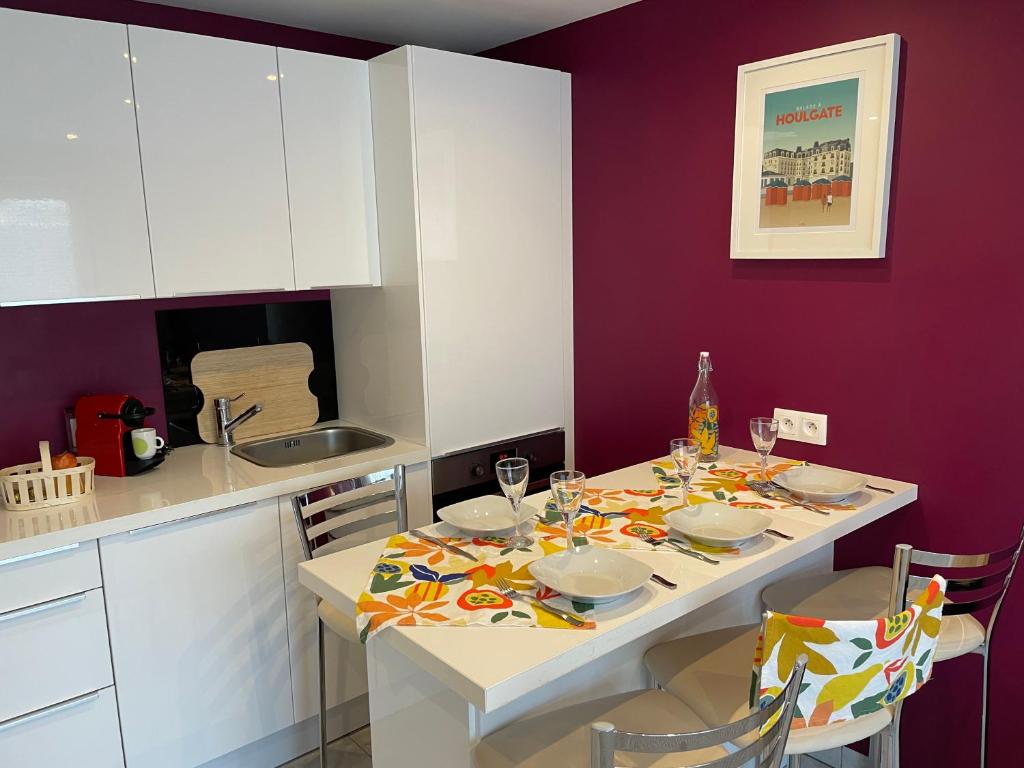 une cuisine avec une table et un mur violet dans l'établissement 2 pièces Les Coquillages - Hypercentre et Plage, à Houlgate