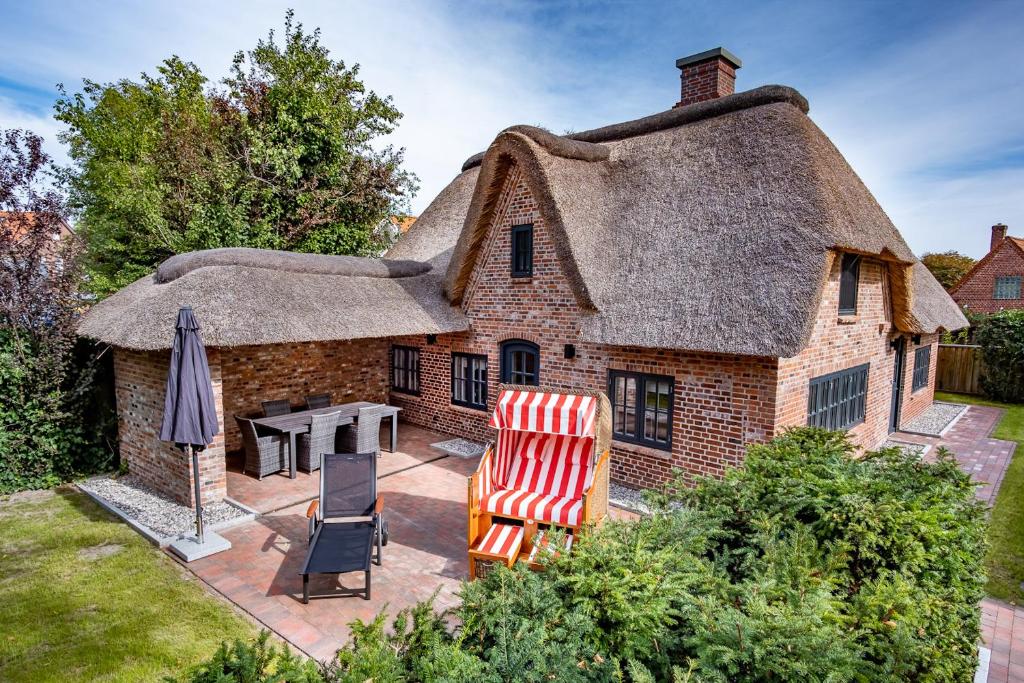a thatched house with a patio and a table and chairs at Dünenkate Dünenkate in Sankt Peter-Ording