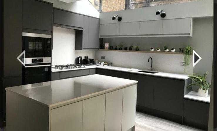 cocina con armarios blancos y encimera blanca en Stylish home in Streatham., en Londres