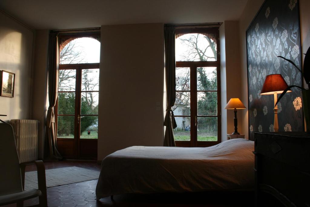 a bedroom with two windows and a bed in it at B&B Le Logis de Bois Renard in Saint Laurent Nouan
