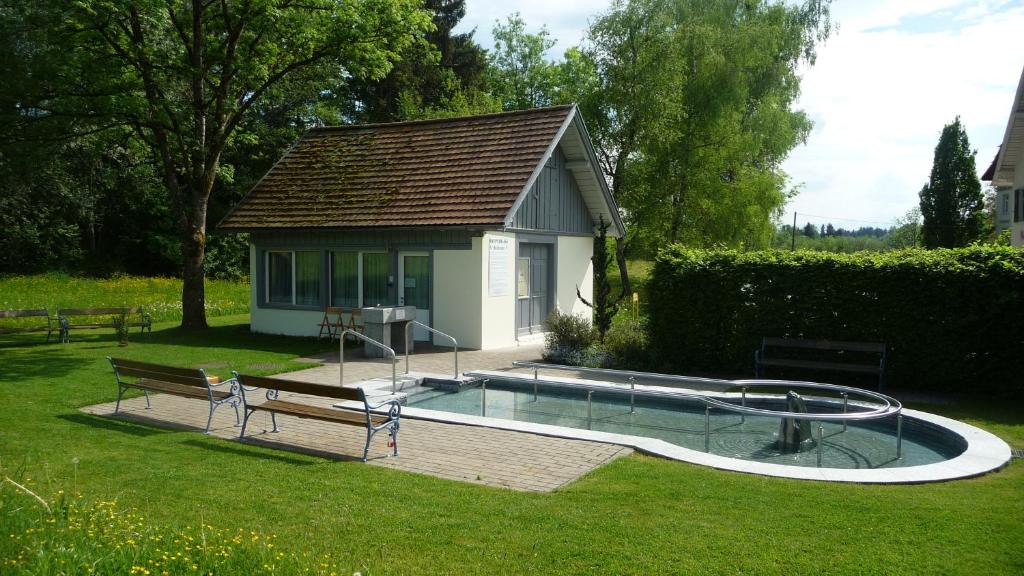 a swimming pool with a bench and a house at Gasthof - Auszeit im Bad Diezlings - Adults only in Hörbranz