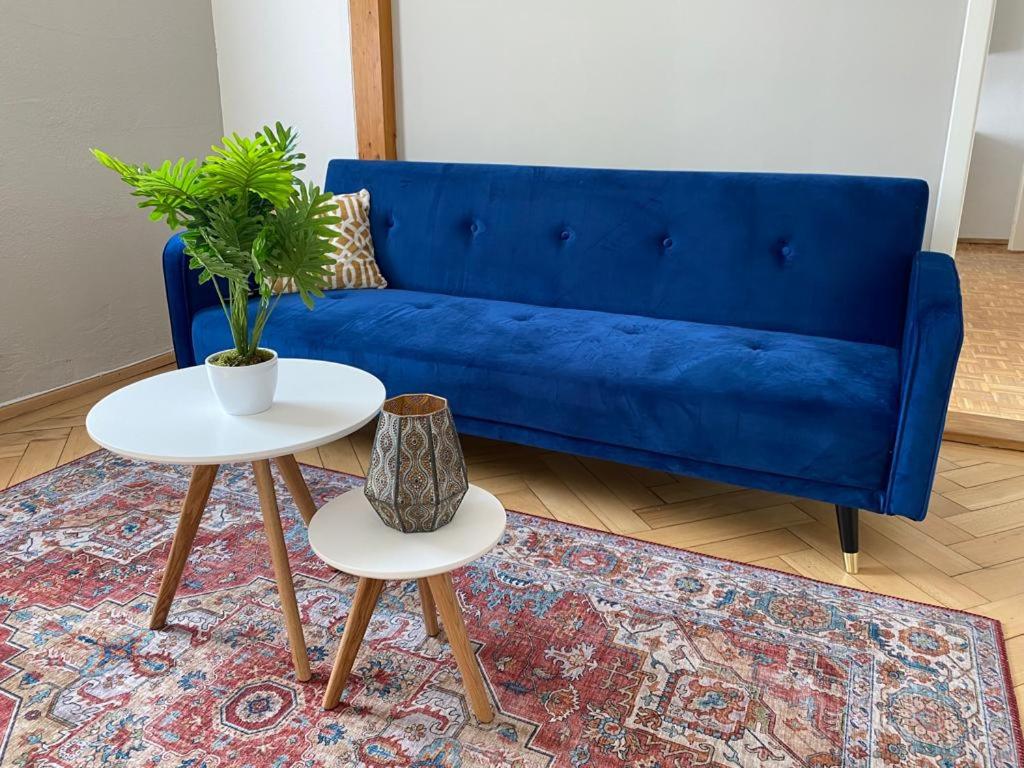 a living room with a blue couch and two tables at Gasthof - Auszeit im Bad Diezlings - Adults only in Hörbranz