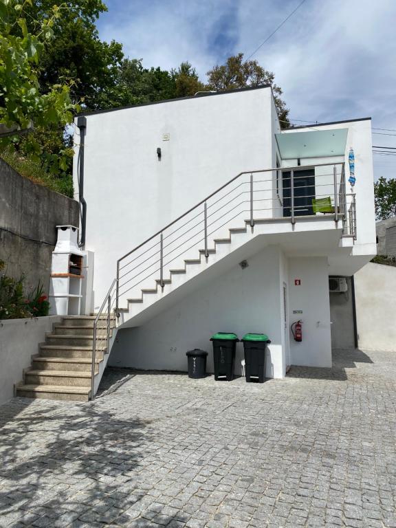 - un bâtiment blanc avec des escaliers et deux poubelles dans l'établissement Cantinho Verde T1, à Gerês