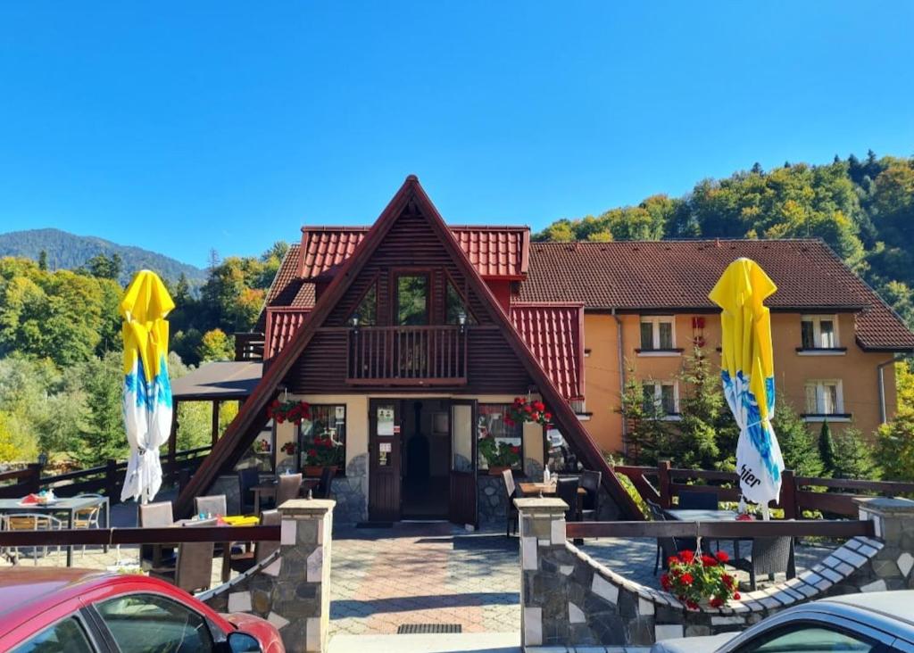 a building with a roof with yellow and blue bows at Motel “La Butuci” in Timisul de Jos