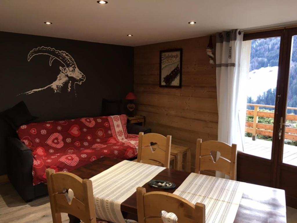 une salle à manger avec une table et un canapé dans l'établissement Charmant T2 avec terrasse ensoleillée, proche navette, animaux admis, parking - FR-1-467-32, au Grand-Bornand
