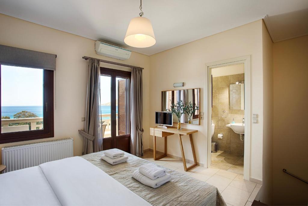a bedroom with a bed and a bathroom with a view of the ocean at Aithra -Agios Petros Andros in Gavrio