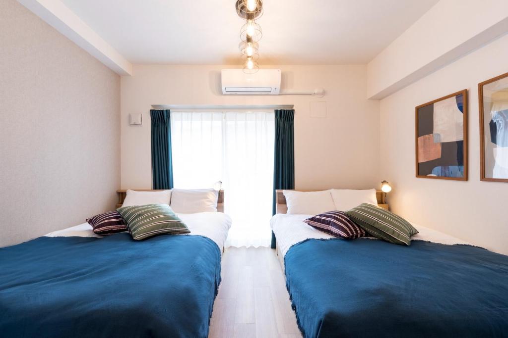 福岡的住宿－SG RESIDENCE INN HAKATAEKIMINAMI - Vacation STAY 61959v，蓝色和白色的客房内的两张床