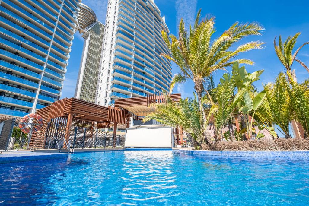 una piscina con palmeras y edificios en Sunset Drive Resort Apartment 5-10 Poniente Beach, en Benidorm