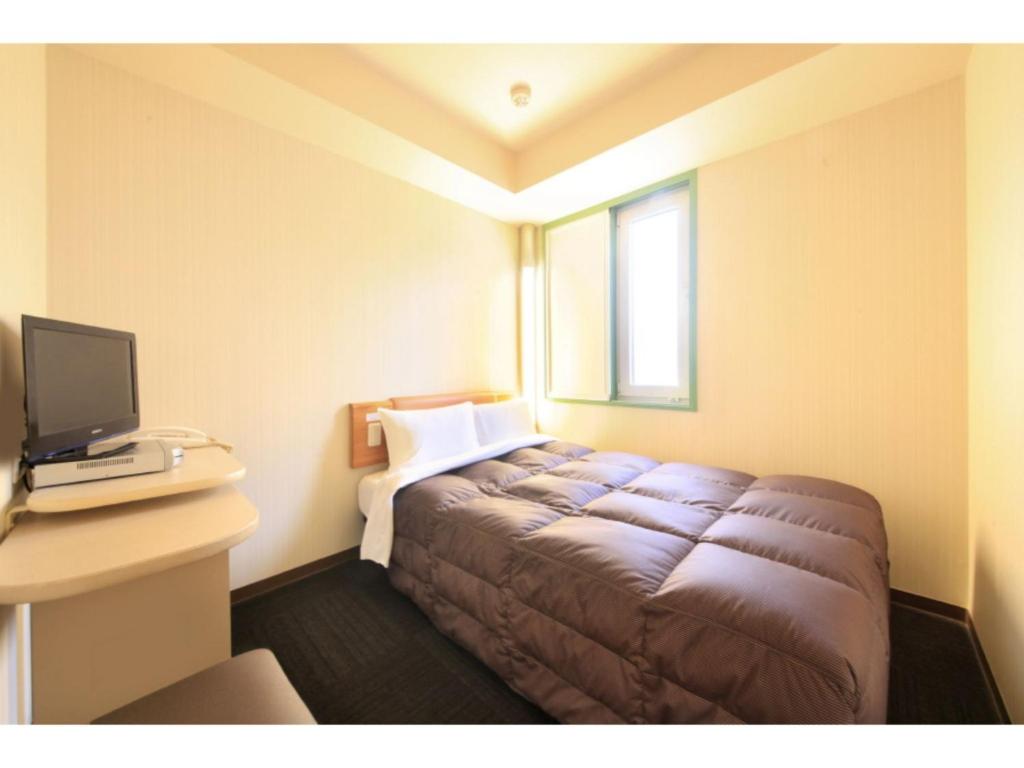 a hotel room with a bed and a desk with a computer at R&B Hotel Sendai Hirosedori Ekimae - Vacation STAY 39668v in Sendai