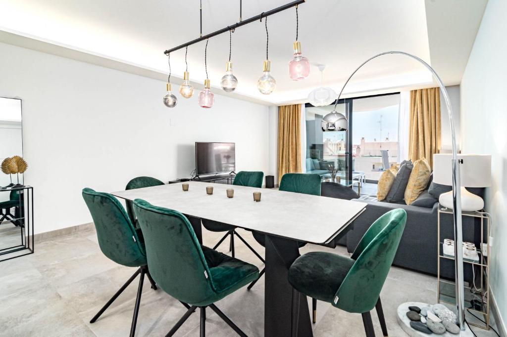 a living room with a table and green chairs at INF45P- modern 3 bed city apartment next to beach in Estepona