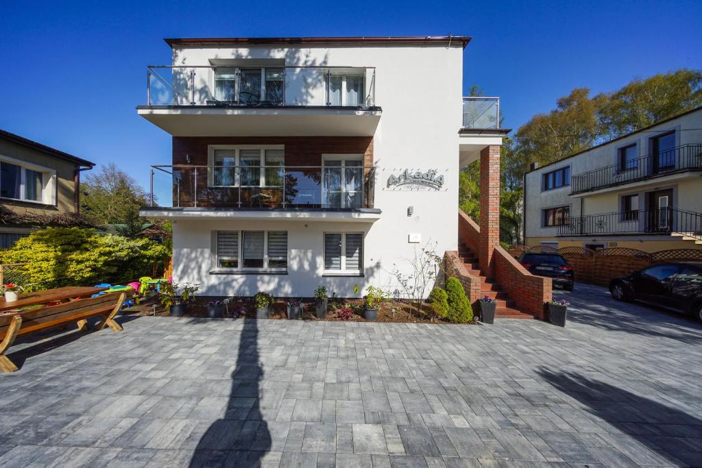 een groot wit gebouw met een balkon en een parkeerplaats bij Willa Arkadia in Pobierowo