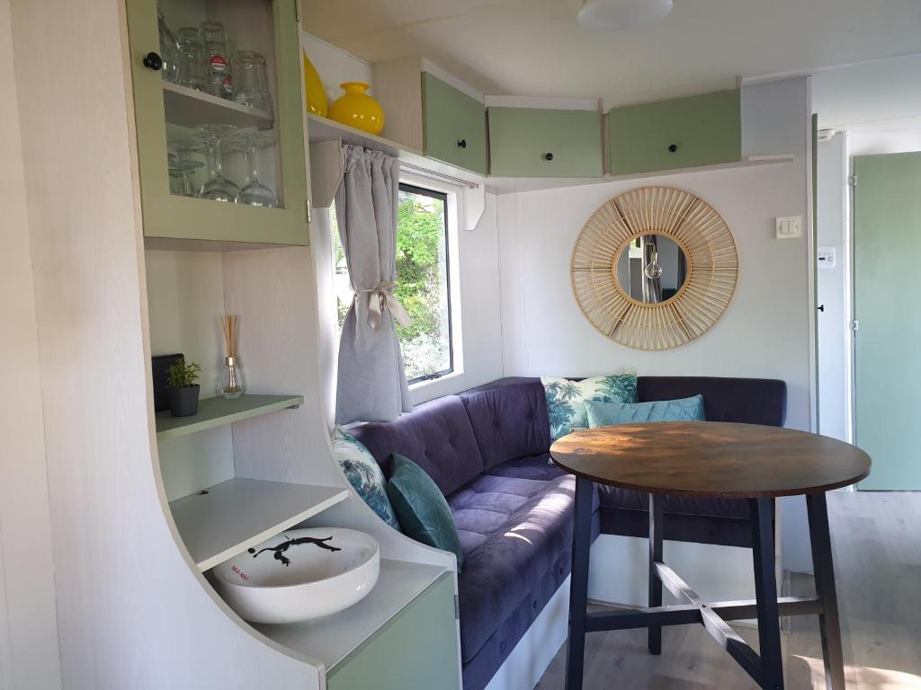 een woonkamer met een paarse bank en een tafel bij Vintage stacaravan Fereale Grou in Grou