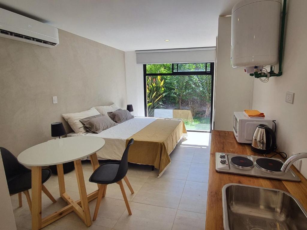 a bedroom with a bed and a table and a kitchen at The owl lodge in Ciudad Lujan de Cuyo