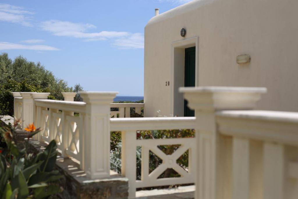 a white house with a white fence and a door at Aithra -Agios Petros Andros in Gavrio