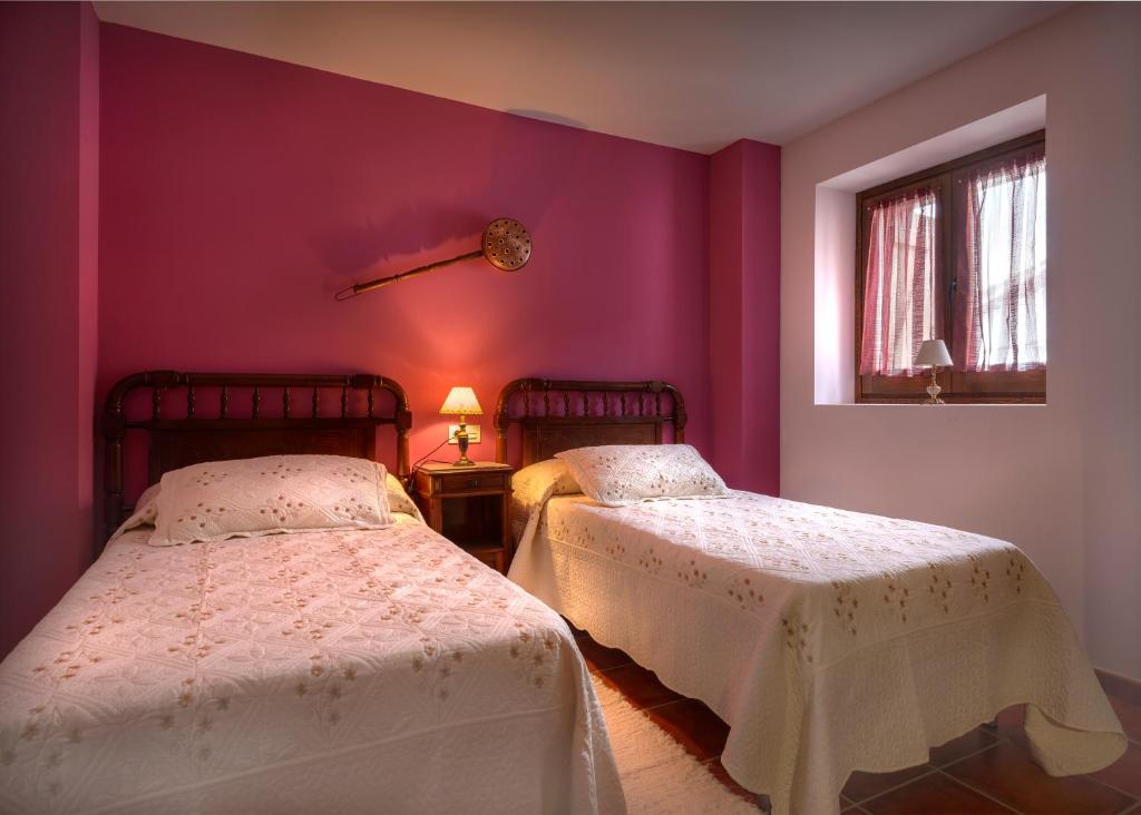 2 łóżka w pokoju z fioletowymi ścianami w obiekcie Paloma w mieście Ansó