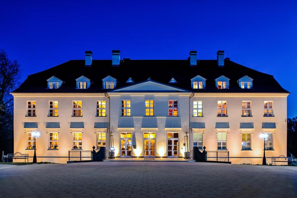 a large white building with lights on at night at Schloss Rattey in Schönbeck