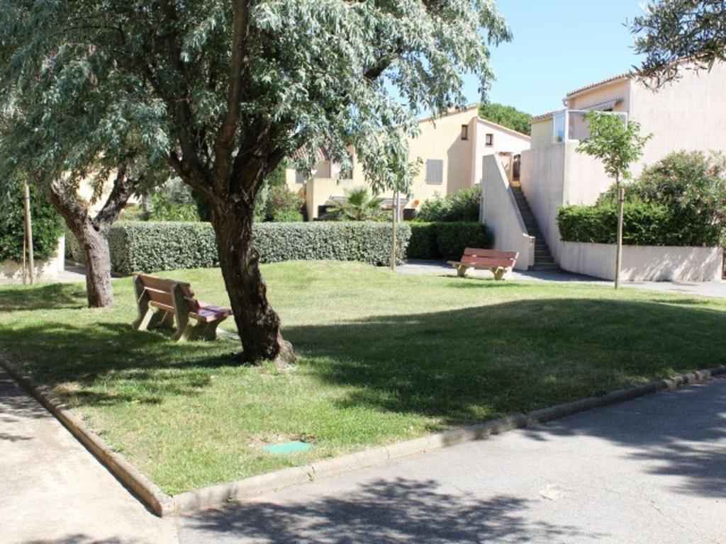 un parc avec deux bancs et un arbre dans l'établissement Appartement Gruissan, 2 pièces, 6 personnes - FR-1-229-777, à Gruissan