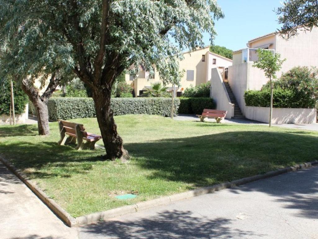 un parc avec deux bancs et un arbre dans l'établissement Appartement avec Terrasse, 6 Couchages, à 2 Pas de la Plage - Gruissan - FR-1-229-777, à Gruissan