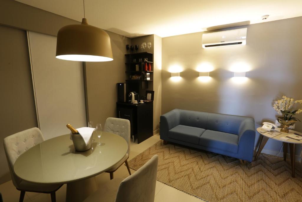 a living room with a table and a blue couch at Uchôa Teresina Hotel in Teresina