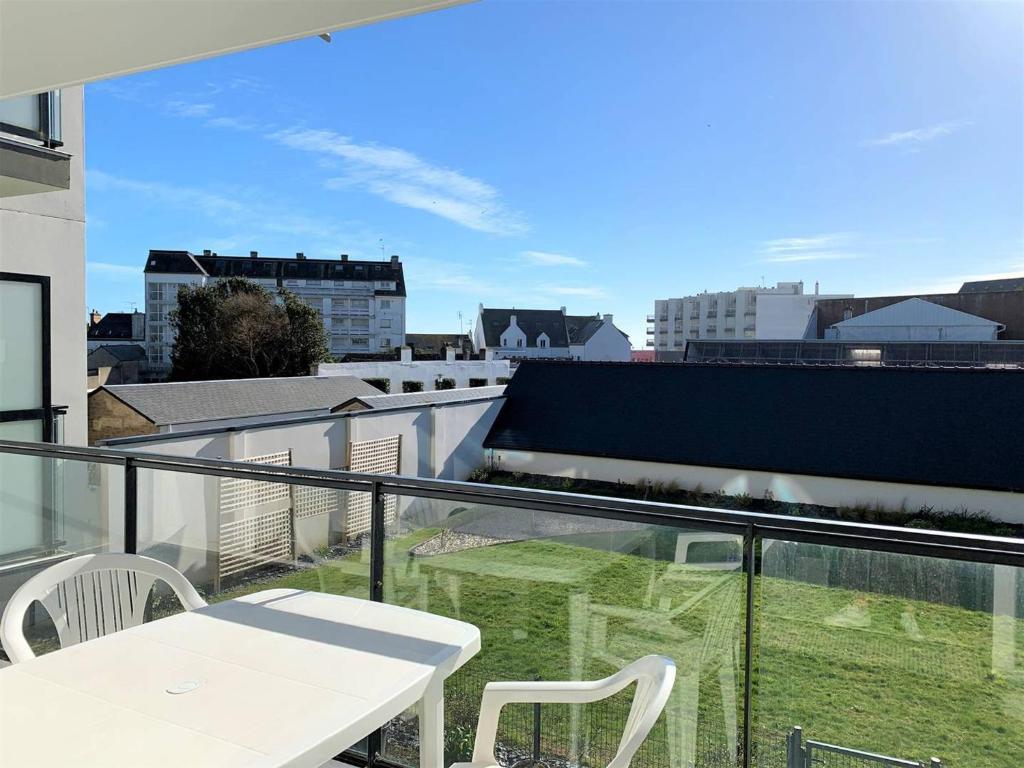 un balcon avec une table et des chaises blanches sur un immeuble dans l'établissement Charmant T2 à Quiberon, balcon sud, parking, à 300m des commerces et plage - FR-1-478-162, à Quiberon