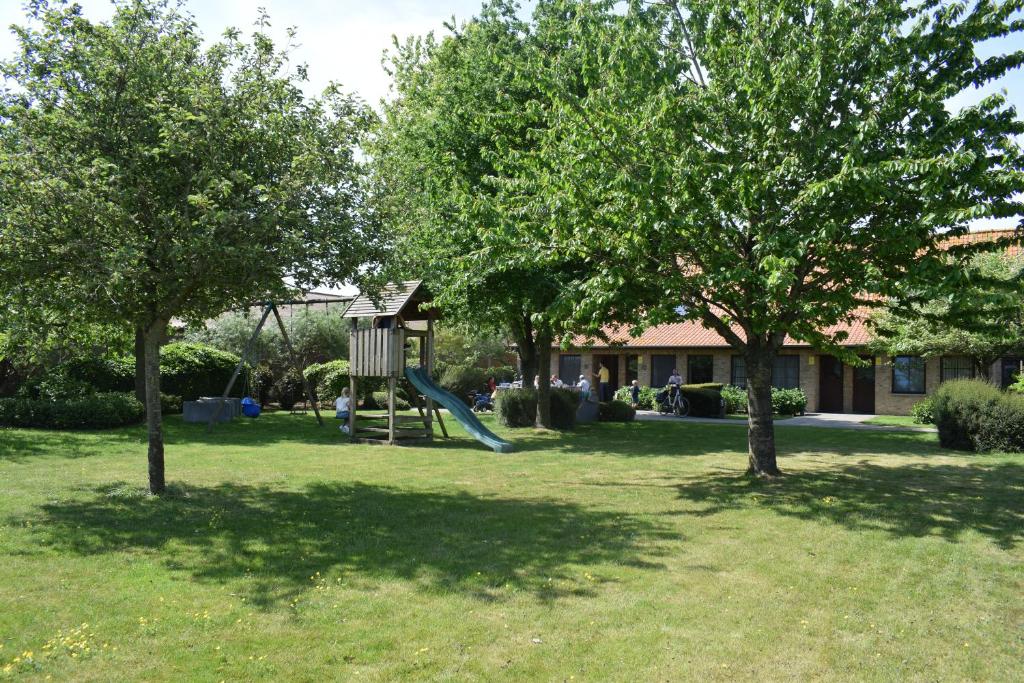 een speeltuin met een glijbaan in een tuin met bomen bij DE MEIBOOM vakantiehoeve tot 21 pers in Langemark