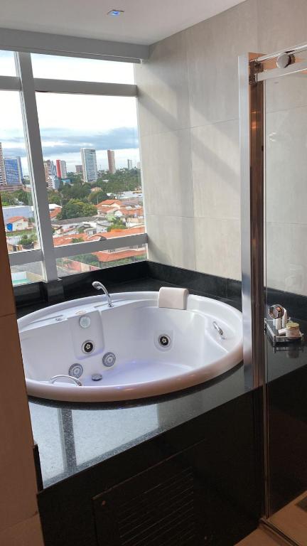 a bath tub in a bathroom with a large window at Uchôa Teresina Hotel in Teresina