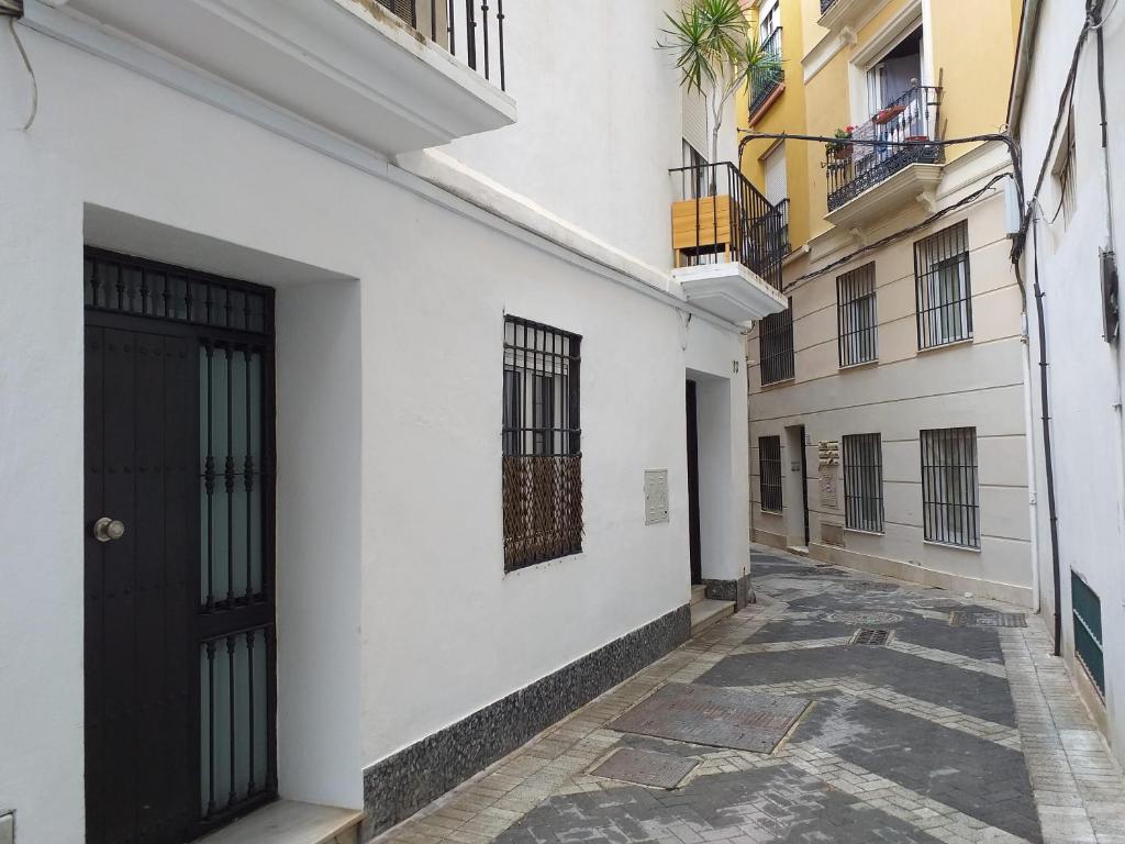 un callejón con edificios blancos y una puerta negra en Malaga Ensuites City Centre, en Málaga