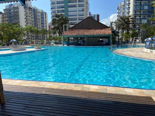 uma grande piscina azul com um edifício em Condomínio Ocean Park módulo 6 proximo a praia e shopping Riviera de São Lourenço em Riviera de São Lourenço